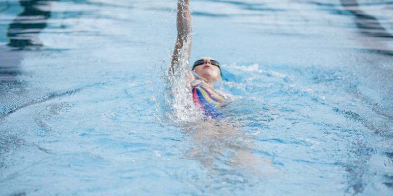 young woman swimming in swimming pool backstroke STBF00346